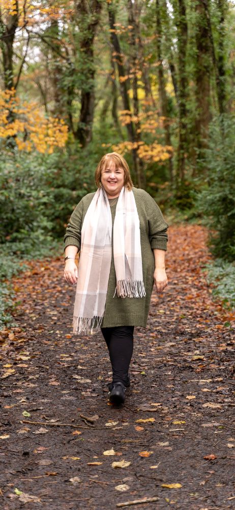Jackie McGloughlin I Energy Flows walking in the woods wearing a large scarf