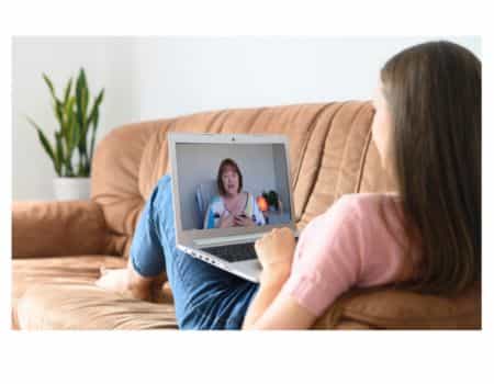 Woman sitting on couch with laptop participating in an online group workshop from Jackie holistic therapist at Energy Flows