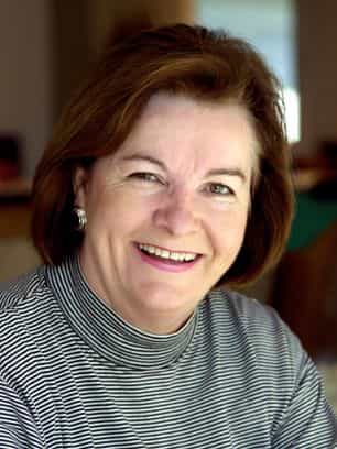 Smiling woman with dark hair wearing a striped black and white turtleneck and pearl earrings