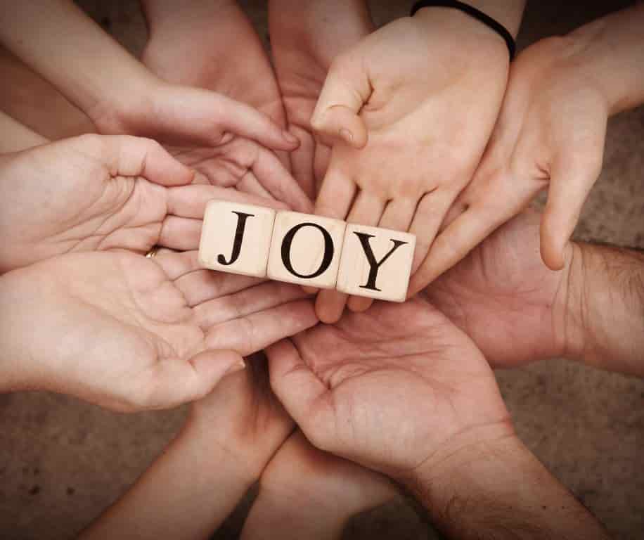 Joy is the centre tiles and supported by many hands holding it.